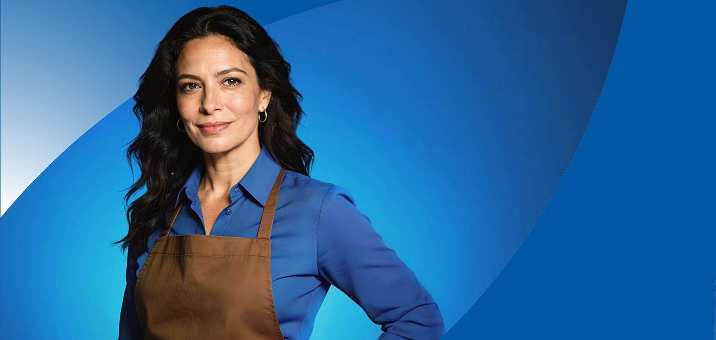 Mujer sonriente, vestida con camisa azul y delantal cafe